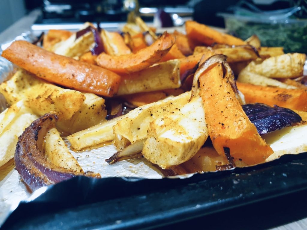 Close up image of assorted roasted winter vegetables (carrots, parsnips, and onions)