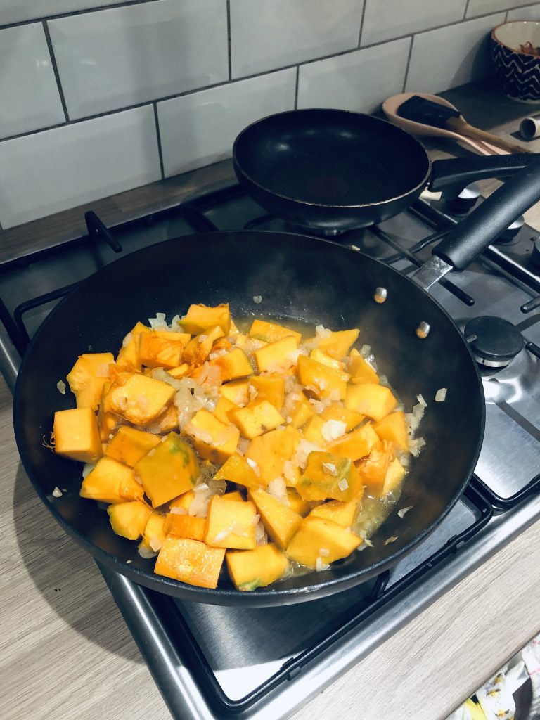 Top down image of a pan with the pumpkin cooking in a wok.