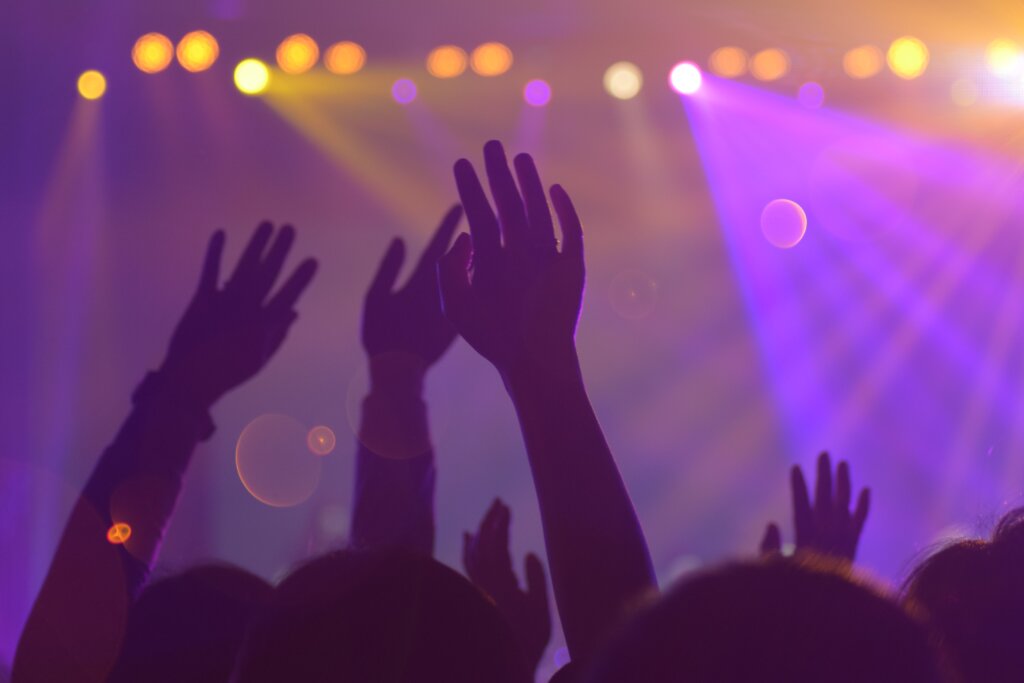 Hands up in a nightclub. Purple lighting.