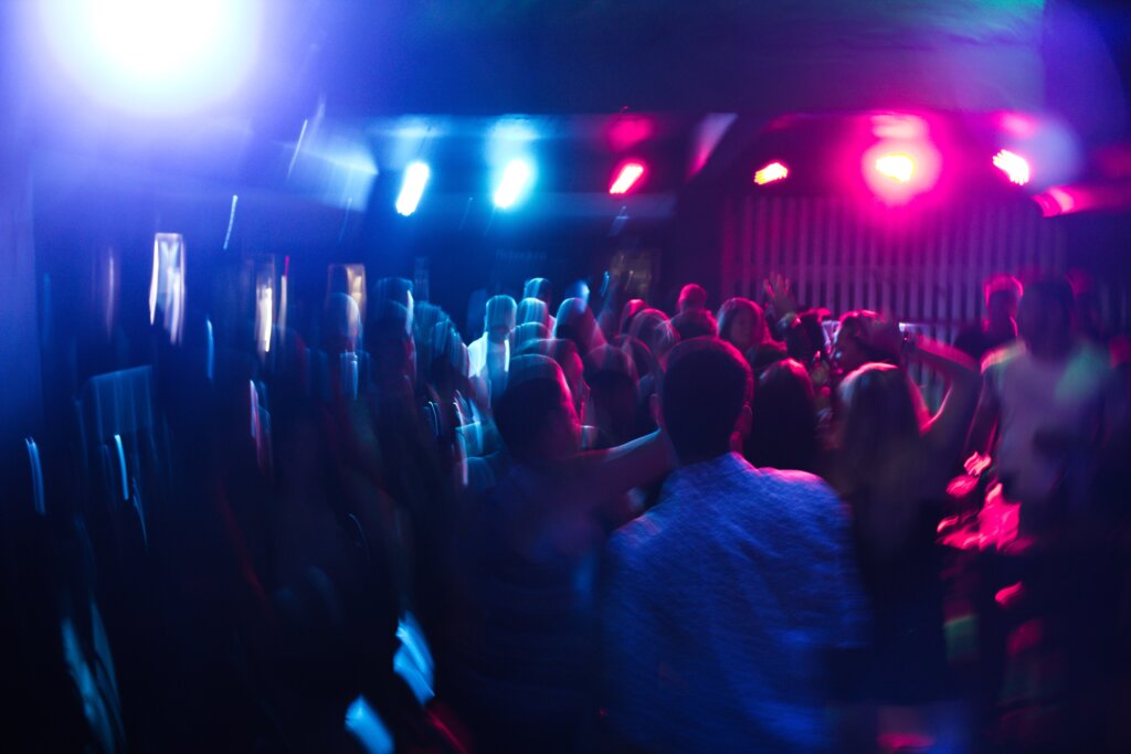 A blurry image of people dancing in a club with pink and blue lighting 