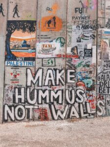 separation wall in bethlehem that reads "make hummus not walls" in graffiti.